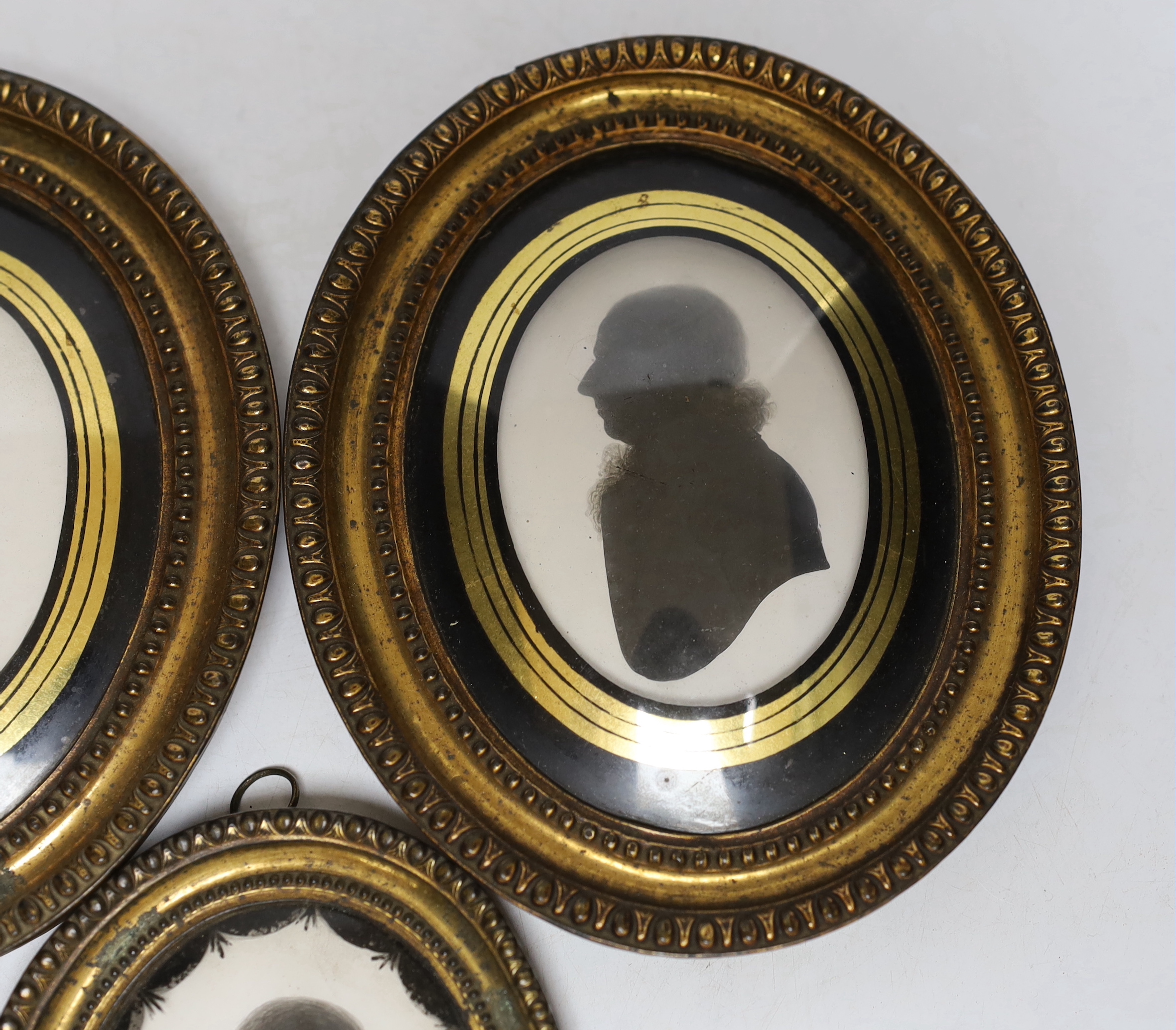 Three late Georgian silhouette portraits, verre eglomise mounts, largest 17cm high